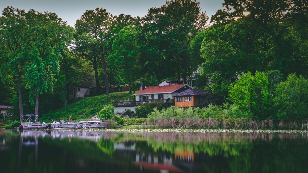 Home Serene lakefront house surrounded by lush green trees and calm waters, perfect for relaxation.