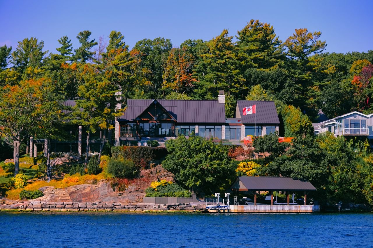 Home Beautiful lakefront house surrounded by colorful autumn trees in Canada.