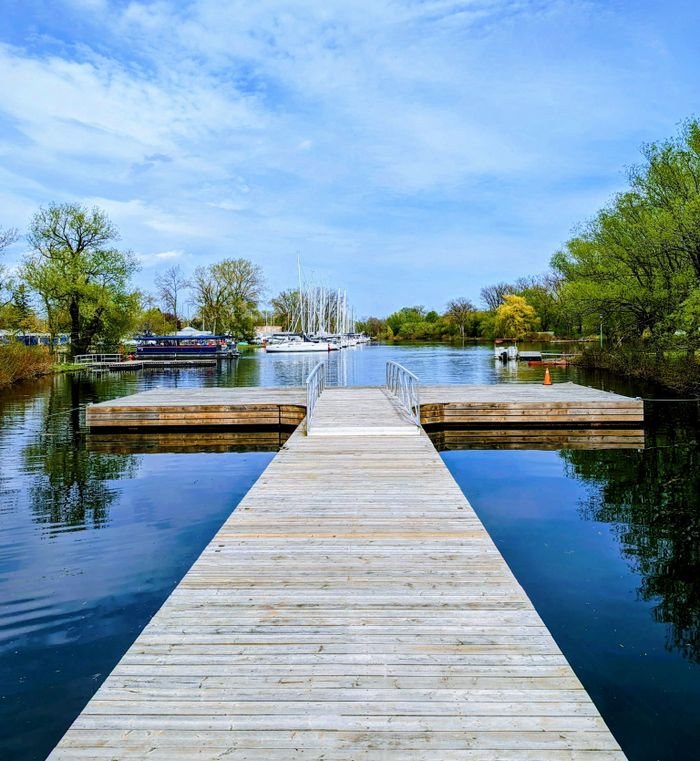 Services A serene view of a wooden jetty extending into a marina with boats in Toronto, Canada.